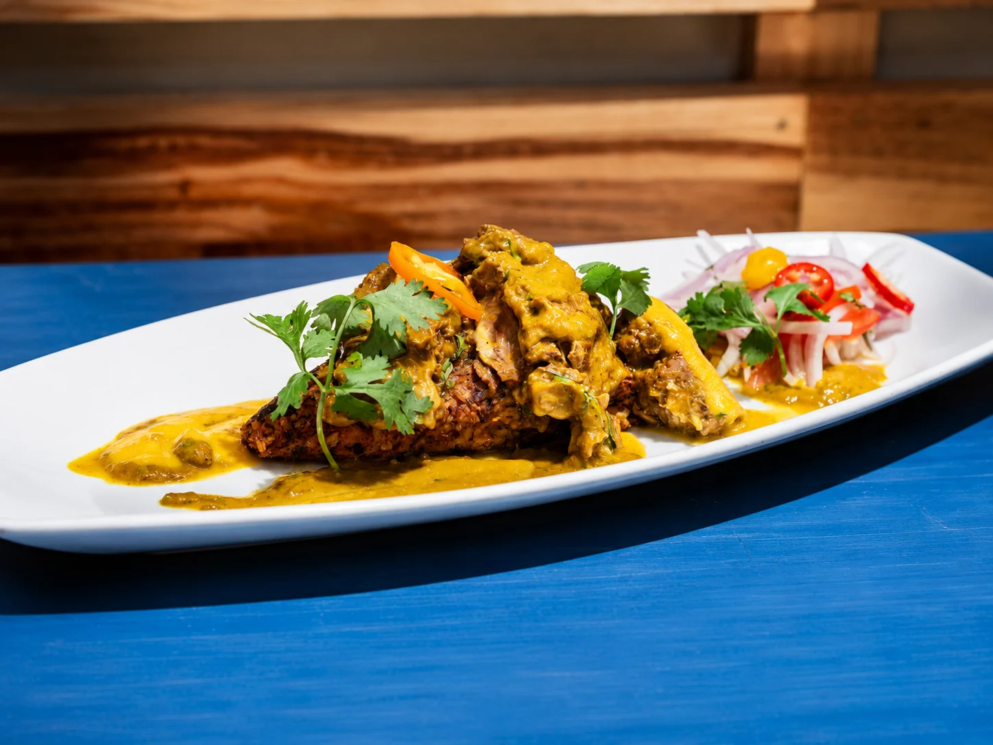 Tacu tacu con cabrito servido en plato alargado en ManQura