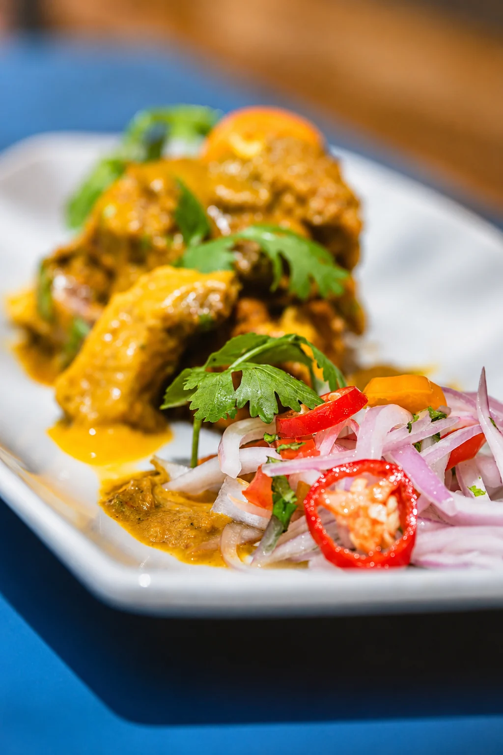 Detalle de salsa criolla y cabrito en tacu tacu de ManQura